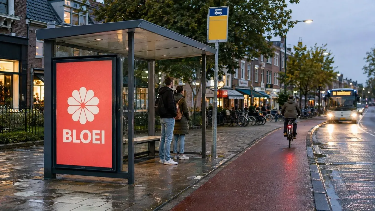 Een verlicht reclamepaneel bij een bushokje in de stad, met wachtende passanten