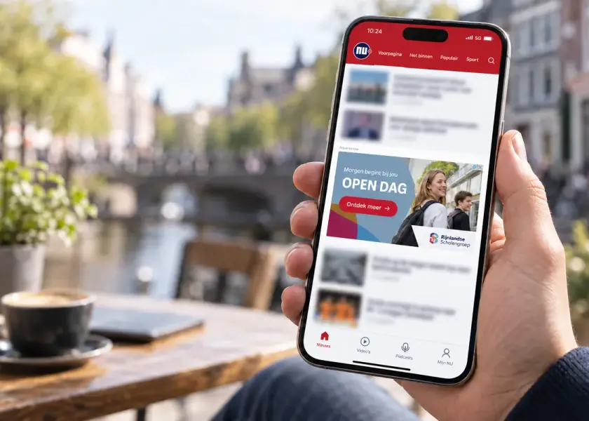 Hand met een telefoon waarop een advertentie in een nieuws-app te zien is